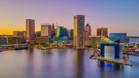 Baltimore skyline at dusk with illuminated skyscrapers reflected in the calm harbor water